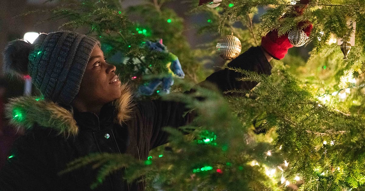 Student hanging ornament on Christmas tree